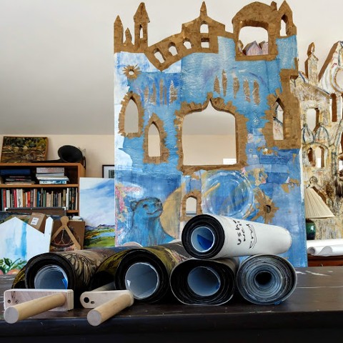 A stack of crankie scrolls in front of "The Big Blue Bear Theater"  painting