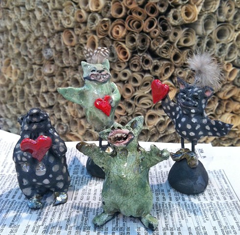 four little monsters made of raku ceramics and feathers by lisa schumaier