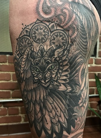 this is a tattoo done in a gothic dark art style by amanda marie tattooer of an owl spirit animal with a mandala halo and a pocket watch done in black and grey with soft shading amanda works at ace of wands tattoo in san pedro los angeles california 