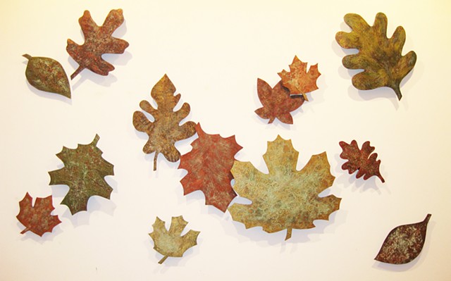 Elevated wall art sculptures made of wood shaped leaves with metallic texture.
