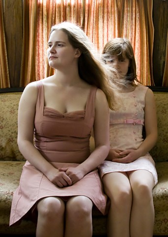 Self portrait of sisters in pink dresses, one with long hair blowing in front of the other's face. 