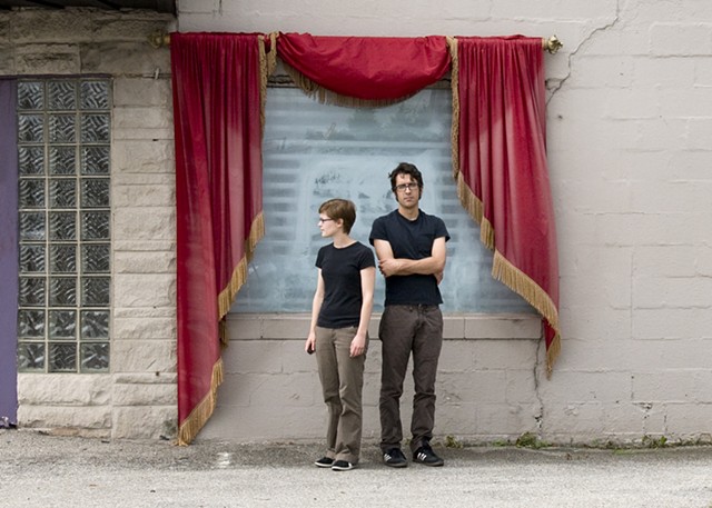 Self portrait with boyfriend in front of red curtain. Wearing matching outfits, black shirt and brown pants. 