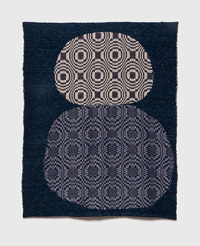 A sun and a moon sit stacked on top one another with Inlay background and overshot pattern foreground
