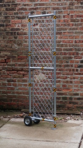 Robert Fields, TOO MUCH! ...(Demasiados!), 2019. 69" H x 22" W x 12 " D. Galvanized and painted steel pipe, wire fencing and hardware, with reflective, adhesive tape and rubber-tired wheels. A Contemporary, Performance Artwork. 