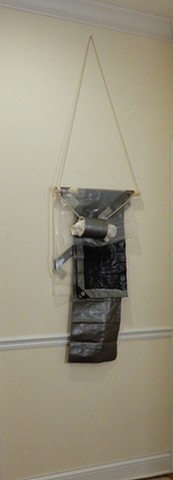A contemporary, wall-hung minimalist abstract sculpture with elements of formalism & materiality. A mixed media assemblage of polyethylene tarpaulin & film, adhesive tape, wood, rope and PVC pipe. "The Doc's In." 2018. By Robert Fields. 