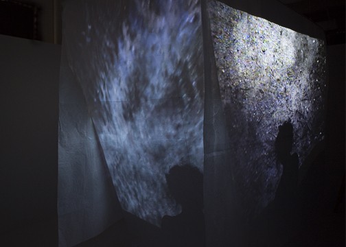 installation of suspended, woven, waxed paper walls with multichannel video projection
