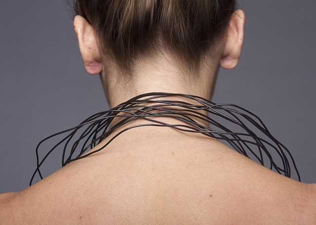 a one-of-a-kind sculptural neckpiece that is composed of thirteen individual hand formed steel wire necklaces with black vine charcoal and graphite beads and plastic dip