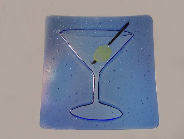 A kiln carved martini in blue glass complete with green olive.