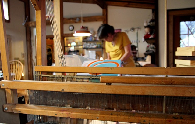 The artist works on a recent piece framed by her loom.