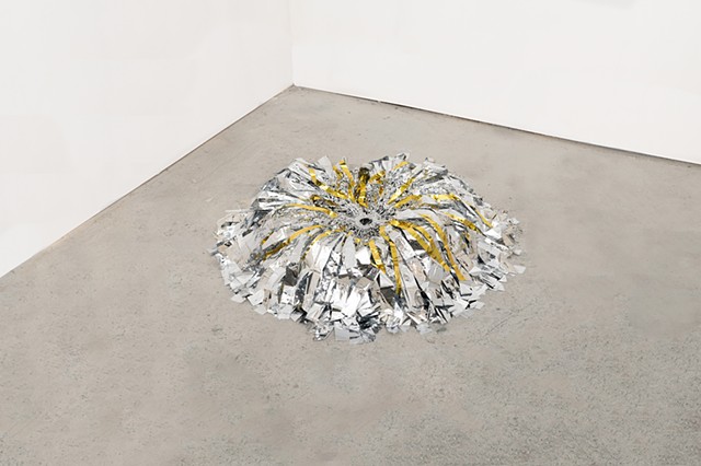 round floor sculpture made from hand netted nylon and knotted silver and gold mylar emergency blankets around a clear silicone ring by José Santiago Pérez