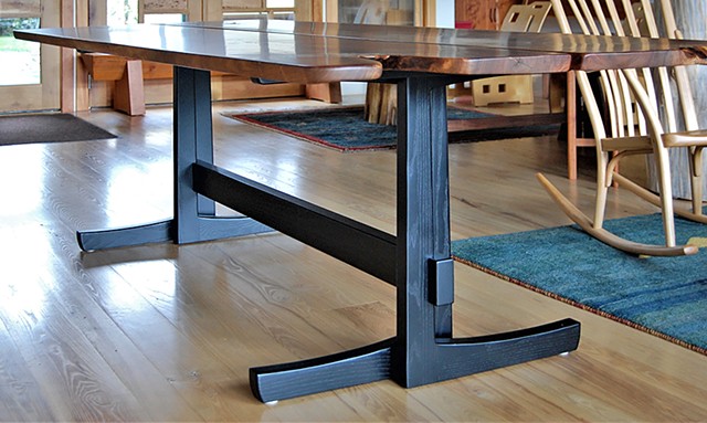 Opposing Leg Trestle Table, book-matched walnut slabs with crotch flame figure on ebonized ash trestle base.  38 in. x 100 in. x 30 in. high.  The table top comes apart at the seam and the base packs flat for shipping.