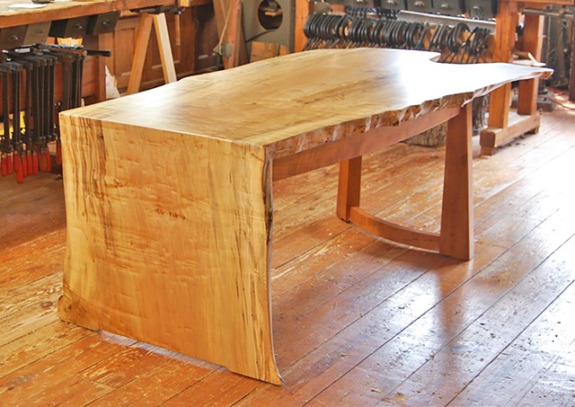 Arnold desk, featuring a one-piece waterfall top made from highly figured maple, locally sourced.  It sits on a cherry base with a single row of drawers.  Approx. 38 x 84 x 30 high.