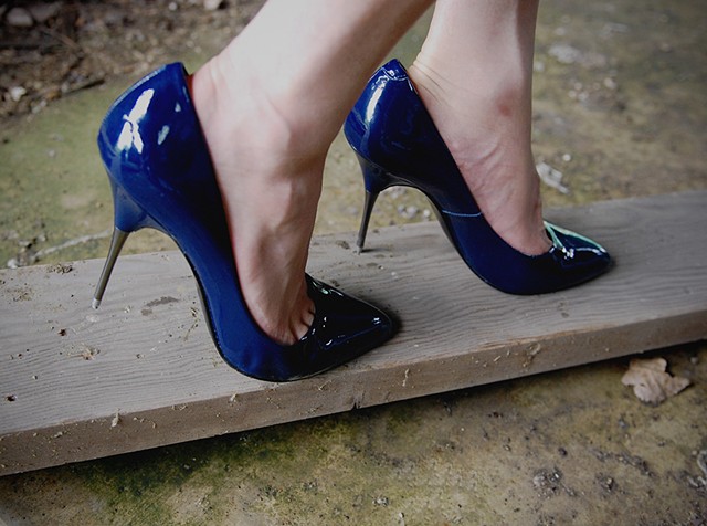 shot of cross dresser in blue steel tipped stilettos putting holes in a board with her shoes photographed by la mouge photo
