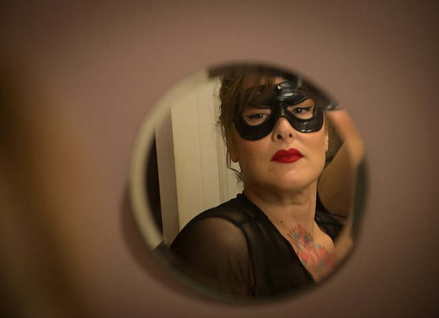 A woman in a cat's eye mask looks in the mirror in a very superior way photographed by La Mouge Erotic Photo 