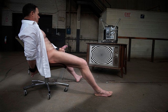 A man with a large cock is masturbating in a warehouse while watching a TV with a spiral on it being hypnotized photographed by La Mouge Photo