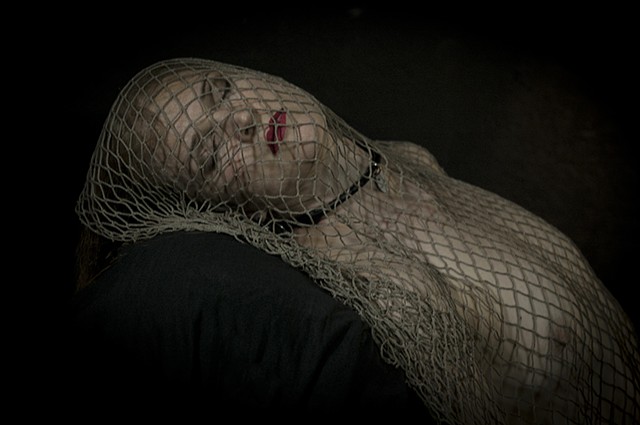 beautiful woman covered in netting lies with her eyes closed on a chaise in a photo by la Mouge Photo reminiscent of old masters' paintings