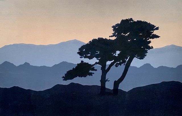 Silhouetted tree at dusk with three mountain ranges