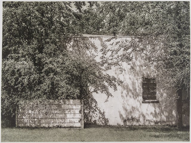 In a small town in North Dakota, a stucco shed wall is dappled by shade in this polymer photogravure print by John Pearson.