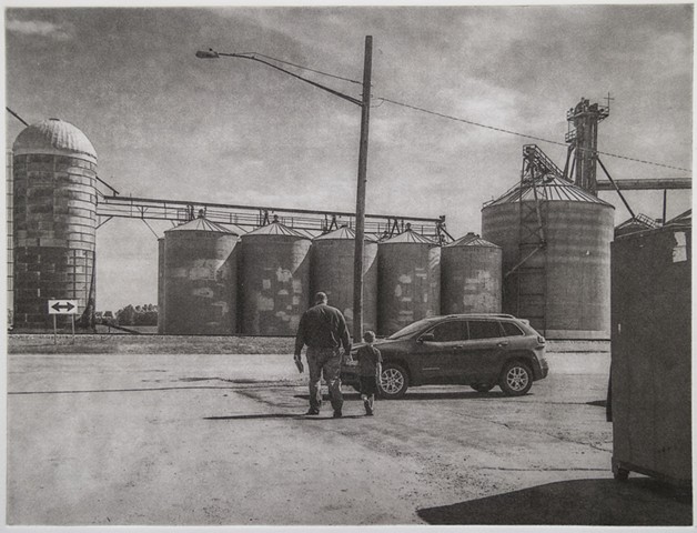 Polymer photogravure intaglio print of a man and young boy walking towards grain elevators in Larimore, North Dakota.