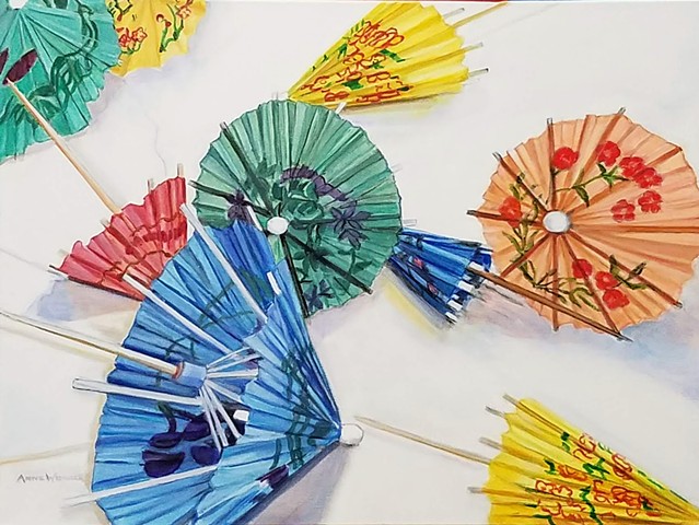 Colorful paper cocktail umbrellas tossed on a white background