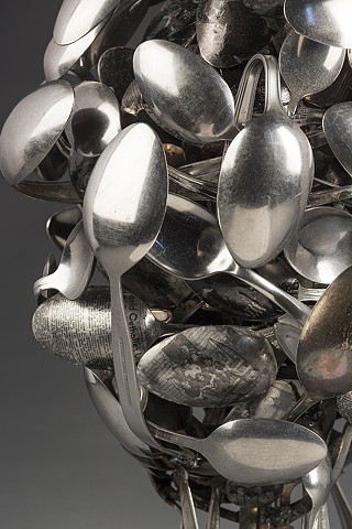 Sculpture made of metal spoons examines mixed black/white identity. Layered spoons covered with personal photos and race-related text references act of eating, feeding on or being fed information about one’s self and asks: How is identity constructed?