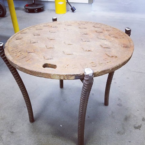 Salvaged manhole cover with heavy steel welded legs