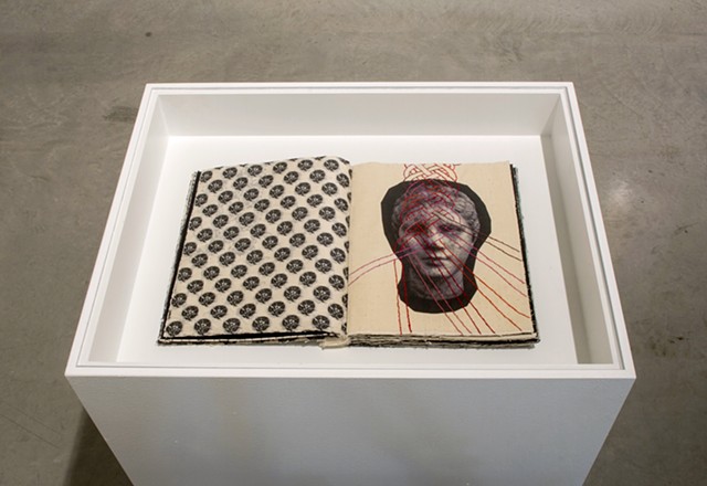 Exhibition view of Notations. Notations is a one of a kind artist's book by Dianna Frid, made with cloth, photographic transfers, and thread. The book focuses on the cloth and hairstyles carved in Greco-Roman Sculpture