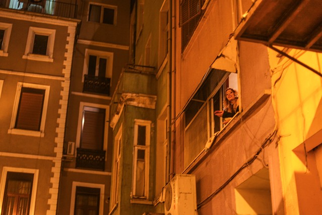 In a neighboring area outside of Taksim Square in Istanbul, Turkey, a sex worker casually hangs out of the window of a brothel, often a means of acquiring late night customers. The majority of Istanbul's legal brothels were closed in January 2013.