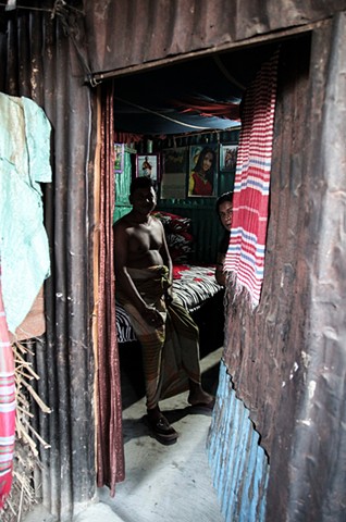 A sex worker peeks out of her room at the C&B Ghat Brothel in Faridpur, Bangladesh after finishing with a customer. Independent sex workers (those without madams) must pay rent on their own rooms.