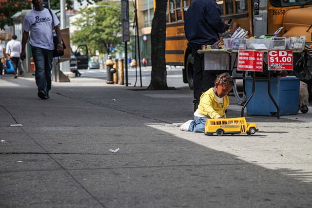 A young boy plays in the middle of 125th Street as his guardians sell items out of their car on September 28, 2015. 