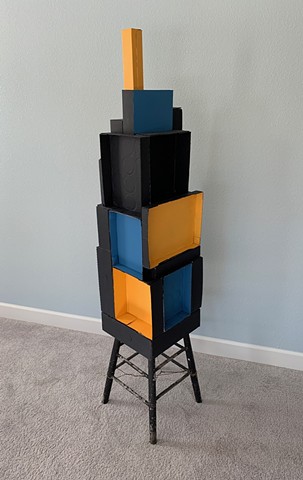 Painted cardboard boxes made into a tower atop an old stool