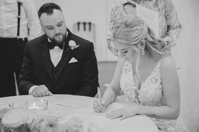 Bride and groom sitting at a table signing their marriage license