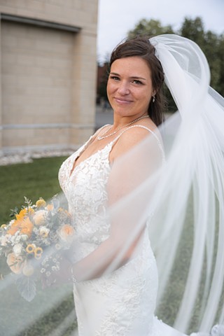 Bride smiling at camera while veil flows in the wind
