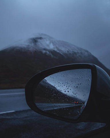 A car mirror reflecting dark mountains and highway road in Iceland