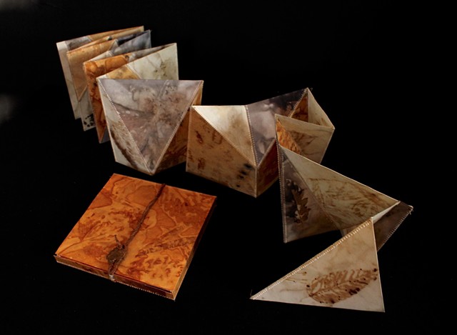 Accordion book assembled from eco-printed pages using geometric pieces based on triangles and polygons.  Book folds flat (as a 6" square) and can be pulled open/extended into multiple forms as a sculpture.  Nests into a box made from the same eco-printed 