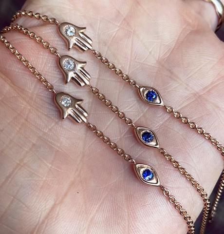 custom hamsa and evil eye rose gold, white diamond and blue sapphire bracelets