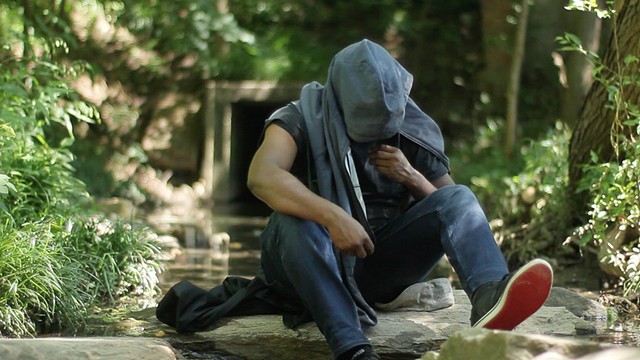 photograph of Black man sitting in woods with blue hoodie by Antoine Williams 