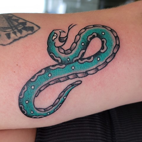 Bold and brightly coloured snake on a woman's arm freshly done by Jason Dopko at Good Times Tattoos in Saskatoon