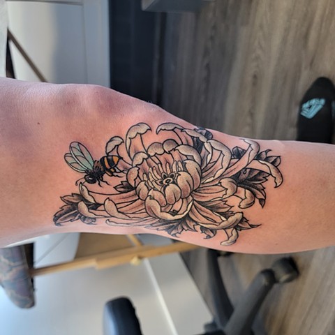 A colorful bee and a black and white flower, on the side of the knee, freshly done Tattoo. Done at Good Times Tattoos a tattoo shop in downtown Saskatoon 
