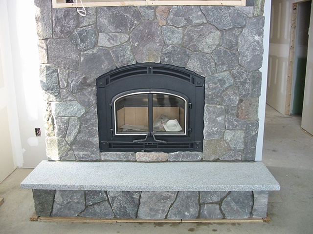 Thin stone veneer around a wood burning fireplace insert.