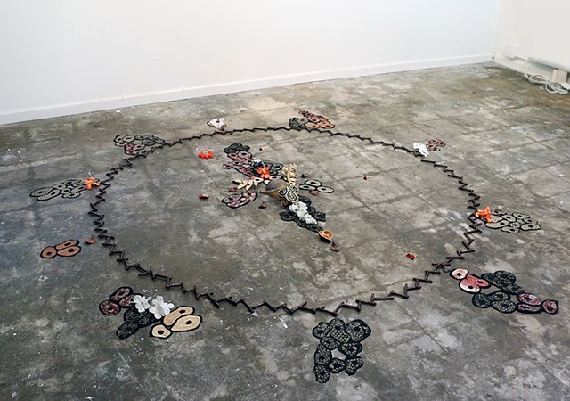 Circular sculpture installed on a concrete floor with various elements that can be rearranged.