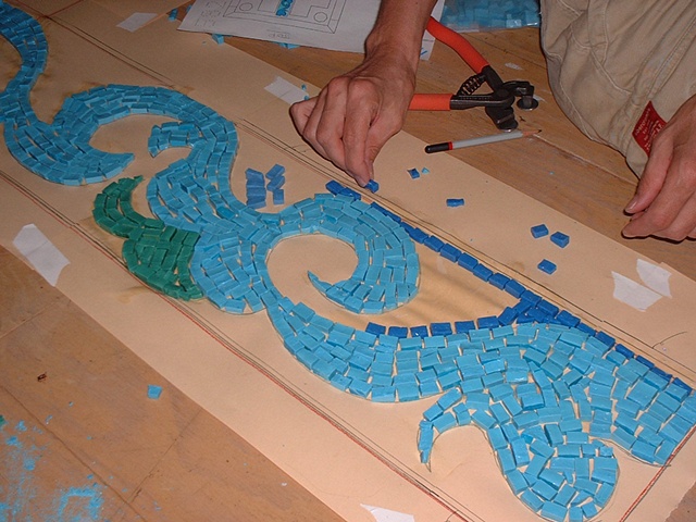 Cutting and gluing the mosaics on the drawn design.