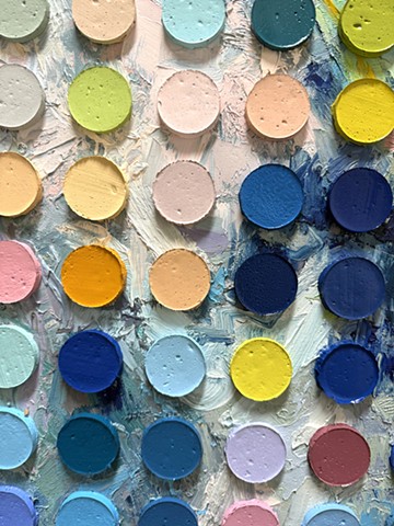 A closer view of the surface of an abstract painting by Daniel Atyim featuring a grid of raised, 3D paint cylinders overlaying a textured background. The multi-colored discs contrast against expressive brushstrokes of blue, yellow orange, white, and violet to create a rhythmic, tactile composition.