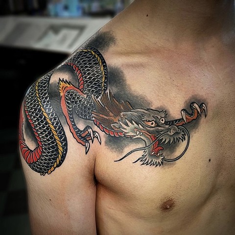 A black traditional Japanese dragon crossing over the shoulder onto the chest