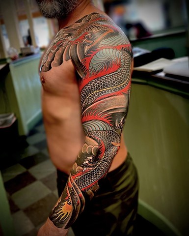 A traditional Japanese full sleeve from chest to wrist, featuring a black dragon with fire