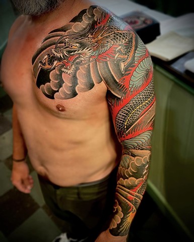 A traditional Japanese full sleeve from chest to wrist, featuring a black dragon with fire