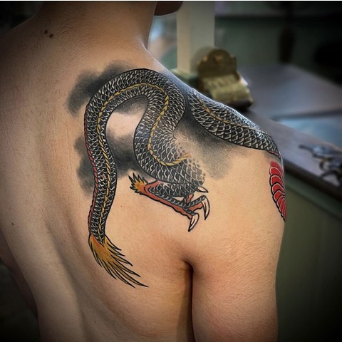 A black traditional Japanese dragon placed from the back of the shoulder to the front