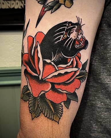 A Western Traditional style, black panther head in a red rose