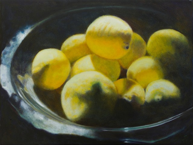 Contrast of strong light on lemons in glass bowl.  Black background  Close up.