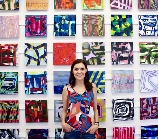 Elyce Abrams in front of paintings from the 100paintings project